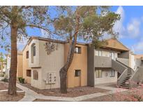 Two-story townhouse showcases neutral tones, complemented by mature trees and walkway access at 3151 Soaring Gulls Dr # 1179, Las Vegas, NV 89128