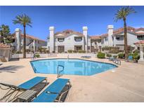 Inviting community pool surrounded by lounge chairs and lush landscaping at residential complex at 713 Wheat Ridge Ln # 102, Las Vegas, NV 89145