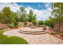 Inviting backyard with brick patio, stone fire pit, seating, and lush landscaping offers space for relaxation at 8340 Jeremiahs Lodge Ave, Las Vegas, NV 89131