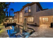 A private backyard pool with lounge seating, a fire pit and lush landscaping is perfect for outdoor living at 10671 Capesthorne Way, Las Vegas, NV 89135