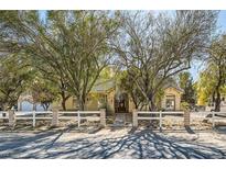 Charming single-story home with mature trees, desert landscaping, and a white fence at 6325 Guy Ave Ave, Las Vegas, NV 89131