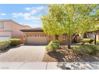 Charming home featuring a well-manicured yard, mature tree, and a brick driveway leading to a two-car garage at 9025 Loggers Mill Ave, Las Vegas, NV 89143