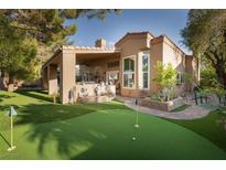 Beautiful backyard featuring a putting green, covered patio, and lush landscaping at 2108 Inverness Dr, Henderson, NV 89074