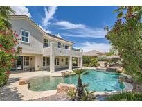 Beautiful backyard pool with a rock waterfall and lush landscaping in a luxury home at 3042 Hammerwood Dr, Las Vegas, NV 89135