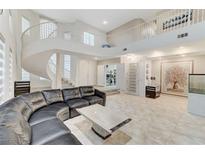 Spacious living room features a spiral staircase, tile flooring and a large leather sofa at 3192 Tullio Way, Henderson, NV 89052