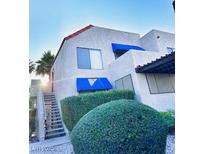 Two-story condo exterior showcasing a classic design and lush green landscaping, complemented by blue awnings and a tiled roof at 4331 Sanderling Cir # 46, Las Vegas, NV 89103