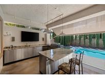 Entertain in style with this outdoor kitchen featuring stainless steel appliances, a marble countertop, and a view of the pool at 5405 San Bellasera Ct, Las Vegas, NV 89141
