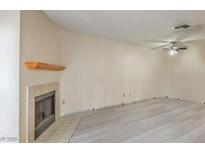 Cozy living room with modern flooring, neutral walls, fireplace, and a ceiling fan at 6861 Tamarus St # 203, Las Vegas, NV 89119