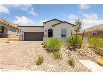 Inviting single-story home features desert landscaping, brick driveway, and a charming covered entryway at 80 Cathedral Wash Pl, Henderson, NV 89011