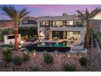 Stunning backyard featuring a pool, spa, lounge area, fire pit, and lush landscaping with palm trees at 12 Desert Lake Ln, Henderson, NV 89011