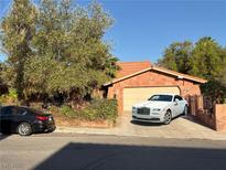 Charming single-story home featuring a red tile roof and a white luxury car parked in the driveway at 3167 El Cedro Cir, Las Vegas, NV 89121