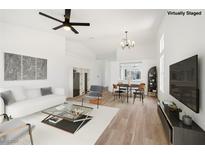 Bright living room features wood floors, white walls, ceiling fan, and white sofa at 3622 Covewick Dr, North Las Vegas, NV 89032