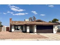 Single-story home featuring a brick chimney, gravel landscaping, and an attached two-car garage at 4276 Aspen St, Las Vegas, NV 89147