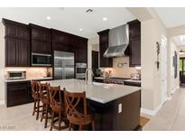 A gourmet kitchen features a large island, stainless appliances, and dark wood cabinetry at 6810 Silver Crescent St, Las Vegas, NV 89148
