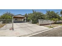 Charming single-story home with a large carport and gated driveway entrance, lush landscaping at 7898 Wishing Well Rd, Las Vegas, NV 89123