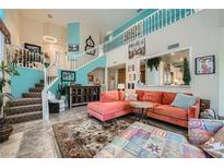 Bright living room with a statement staircase, comfortable coral sofa, and stylish decor at 8713 Nautical Bay Ln, Las Vegas, NV 89117