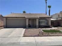 Charming single-story home featuring a well-manicured front yard and a two-car garage and tile roof at 1468 Harmony Hill Dr, Henderson, NV 89014