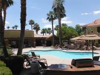 Resort-style swimming pool with palm trees, lounge chairs, and grilling area creating a relaxing community space at 2120 Ramrod Ave # 417, Henderson, NV 89014
