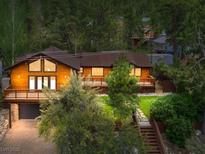 Charming wooded home featuring a large deck, brown metal roof, and an attached garage at 3935 White Fir Way, Mount Charleston, NV 89124