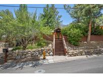 Charming home featuring mature trees, a rock wall, and a welcoming staircase to the front entrance at 3935 White Fir Way, Mount Charleston, NV 89124