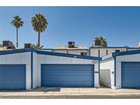 View of exterior featuring two-story home with a blue garage door, palm trees, and clear skies at 4259 Kona Coast Way, Las Vegas, NV 89121