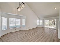 Bright living room featuring wood floors, high ceilings, a modern chandelier, and large windows providing ample natural light at 6944 Emerald Springs Ln, Las Vegas, NV 89113
