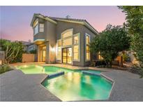 Beautiful backyard pool and spa with lush landscaping and a two-story home with large windows at 912 Pro Players Dr, Las Vegas, NV 89134