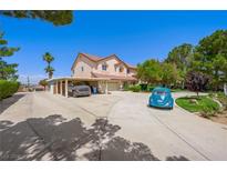 Spacious two-story home with a long driveway, carport, and desert landscaping under a clear blue sky at 1345 Morning Sun Way, Las Vegas, NV 89110