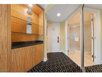 Condo hallway with decorative shelving, white door, and bathroom entrance featuring patterned black and white carpeting at 2000 N Fashion Show Dr # 2704, Las Vegas, NV 89109