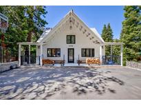 Charming white exterior with an A-frame roof, covered porch, and stone paver driveway and basketball hoop at 4778 Knotty Pine Way, Las Vegas, NV 89124