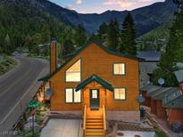 Charming two-story cabin with a green roof nestled in a mountain setting with a street view at 4830 Silver Tip Way, Mount Charleston, NV 89124