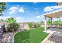 Beautiful backyard features green turf, desert landscaping, and a covered patio with ample space for relaxing at 2504 Libretto Ave, Henderson, NV 89052
