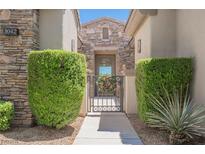 Charming front entrance featuring a stone facade, decorative shrubs, and an inviting wrought iron gate at 3042 Soft Horizon Way, Las Vegas, NV 89135
