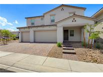 Charming two-story home with brick driveway and a three-car garage in a desert landscape at 1075 Page Park Ln, Henderson, NV 89011