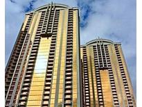 Low angle view of two luxury high-rise condo buildings with gold-tinted windows against a cloudy sky at 125 E Harmon Ave # 1918, Las Vegas, NV 89109