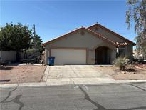 Charming single-story home featuring a two-car garage, arched entryway, and desert landscaping at 4335 Twin Peaks Dr, North Las Vegas, NV 89032