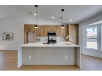 Modern kitchen featuring an island with a waterfall countertop, wood cabinets, and stainless steel appliances at 7133 Tropical Island Cir, Las Vegas, NV 89129