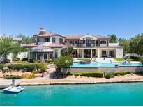 Stunning lakefront home with a private pool, boat dock, and lush landscaping, offering an idyllic outdoor lifestyle at 8725 Newport Isle Ct, Las Vegas, NV 89117
