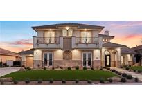 Elegant two-story home featuring dual balconies, stone accents, manicured lawn, and arched entryway at 9605 Verlaine Ct, Las Vegas, NV 89145