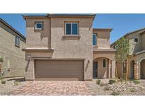 Two-story home featuring a two-car garage and neutral-toned stucco, complemented by a brick paver driveway at 9842 Lost Horse Ave, Las Vegas, NV 89178