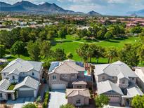 Stunning aerial view of a home with a pool, lush green surroundings, and mountains in the distance at 1551 Boundary Peak Way, Las Vegas, NV 89135