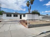 Charming single-story home featuring a white exterior, front fence, xeriscaping, and mature palm trees at 3112 Piedmont Ave, Las Vegas, NV 89102