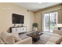 Bright living room with sliding glass doors to balcony and comfortable seating area at 32 E Serene Ave # 207, Las Vegas, NV 89123