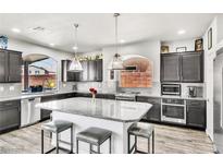 Modern kitchen boasts granite countertops, stainless appliances, and a large center island with seating at 5976 Rockway Glen Ave, Las Vegas, NV 89141