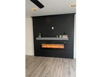 Living room features a black accent wall with modern electric fireplace and wood-look flooring at 8068 Cetus Cir, Las Vegas, NV 89128