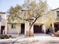 Two-story home featuring a tree in the front yard, a dark brown garage door, and neutral colored walls at 9069 Tantalizing Ave, Las Vegas, NV 89149