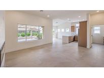 Bright living room featuring tile floors, large windows, and an open floor plan to kitchen at 10421 Linfield Pl, Las Vegas, NV 89134