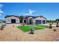 Beautiful single-story home featuring desert landscaping, synthetic grass accents, and a three-car garage at 2891 S Rainbow Ave, Pahrump, NV 89048