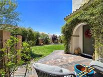 A quaint backyard with lush green grass and access to the home from a brick and stone tiled patio at 396 Blackstone River Ave, Las Vegas, NV 89148
