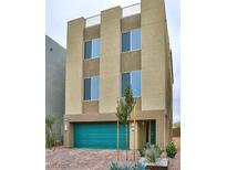Modern three-story home featuring a bold teal garage door, stucco facade, and well-manicured desert landscaping at 8055 Haywood Estate Ave, Las Vegas, NV 89113